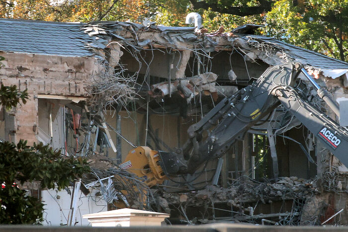 Demolition equipment tearing down a building with rubble and debris during East Wing demolition at White House.