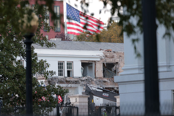 Partial demolition of the East Wing at the White House with an American flag flying in the background.