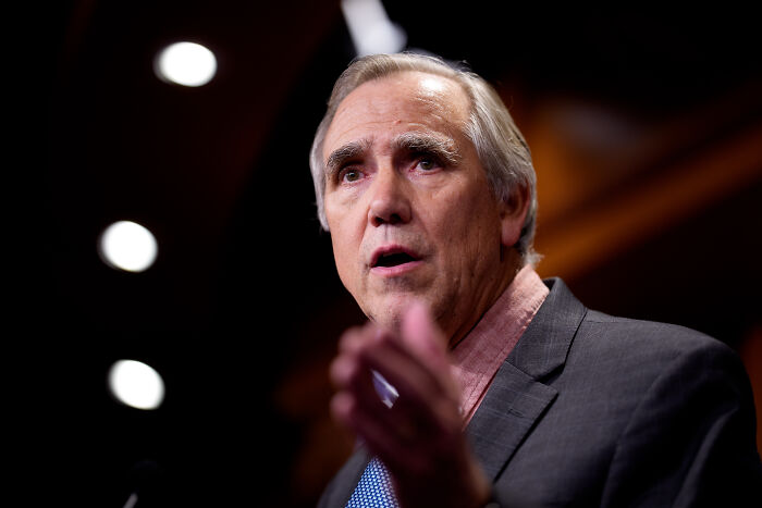 A senator delivering a lengthy floor speech warning of Trump’s authoritarian takeover in a formal setting.