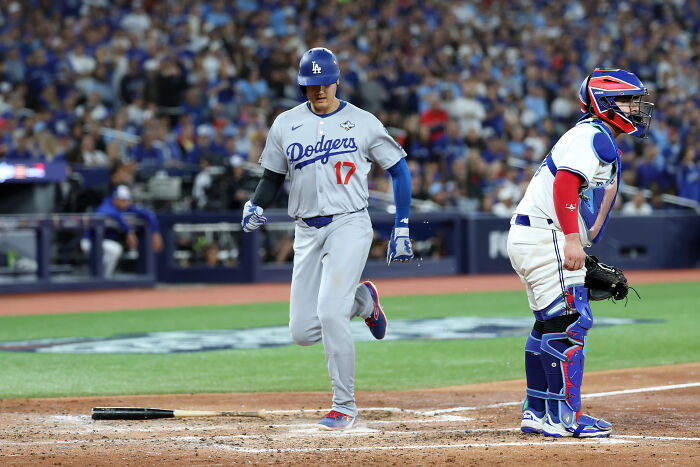Los Angeles Dodgers player rounding the bases during the World Series game with catcher in full gear behind home plate. Los Angeles Dodgers player rounding the bases during the World Series game with catcher in full gear behind home plate.