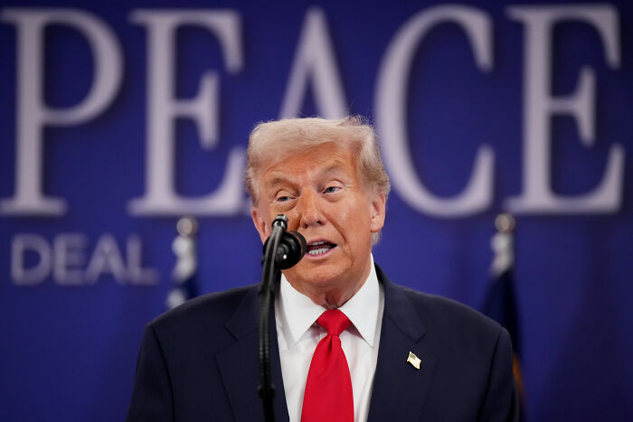 Donald Trump speaking at a podium with a microphone, in a dark suit and red tie at an Asia Summit event. Donald Trump speaking at a podium with a microphone, in a dark suit and red tie at an Asia Summit event.