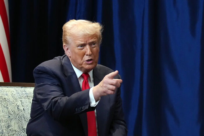 Former President Donald Trump in a dark suit and red tie pointing during a conversation against a blue curtain background related to Stephen King World Series post. Former President Donald Trump in a dark suit and red tie pointing during a conversation against a blue curtain background related to Stephen King World Series post.