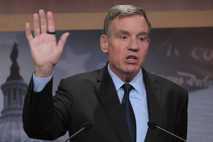 Senator raising hand during a speech criticizing Trump officials for excluding Democrats from boat strikes briefing. Senator raising hand during a speech criticizing Trump officials for excluding Democrats from boat strikes briefing.
