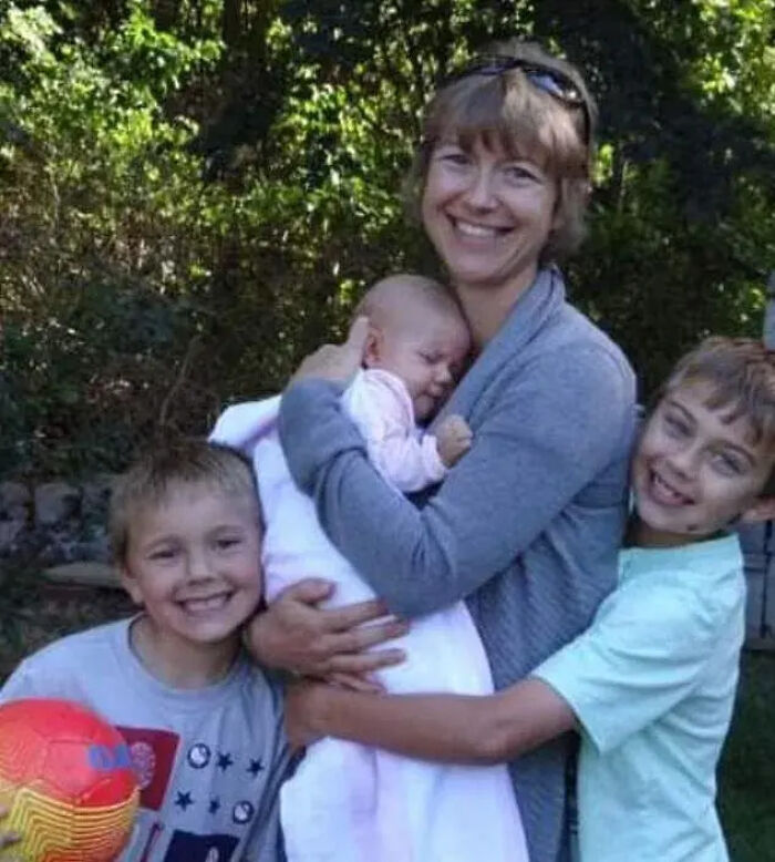 Smiling woman holding baby with two boys hugging her outdoors, related to Florida man unalived wife and children case. Smiling woman holding baby with two boys hugging her outdoors, related to Florida man unalived wife and children case.