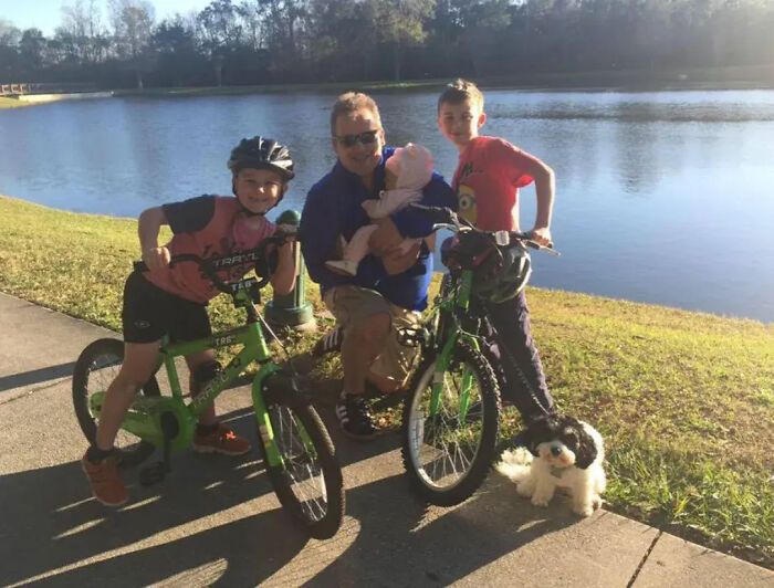 Florida man with wife, three children, and dog by a lake, posing with bicycles and smiling outdoors on a sunny day Florida man with wife, three children, and dog by a lake, posing with bicycles and smiling outdoors on a sunny day