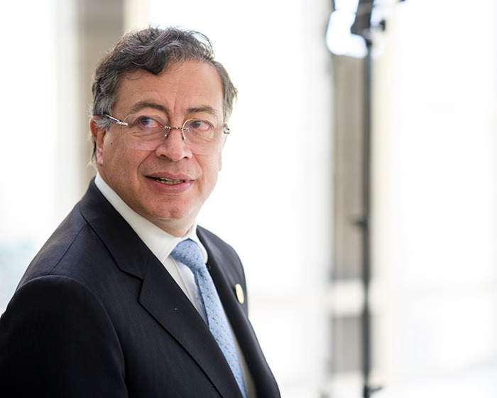 Colombia’s president wearing glasses and suit, looking to the side in a bright indoor setting representing Venezuela analysis.