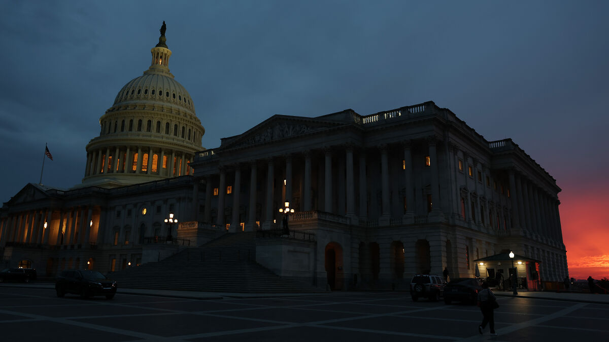 US Capitol building at dusk with lights on, symbolizing government shutdown impacting the nation amid political blame game.