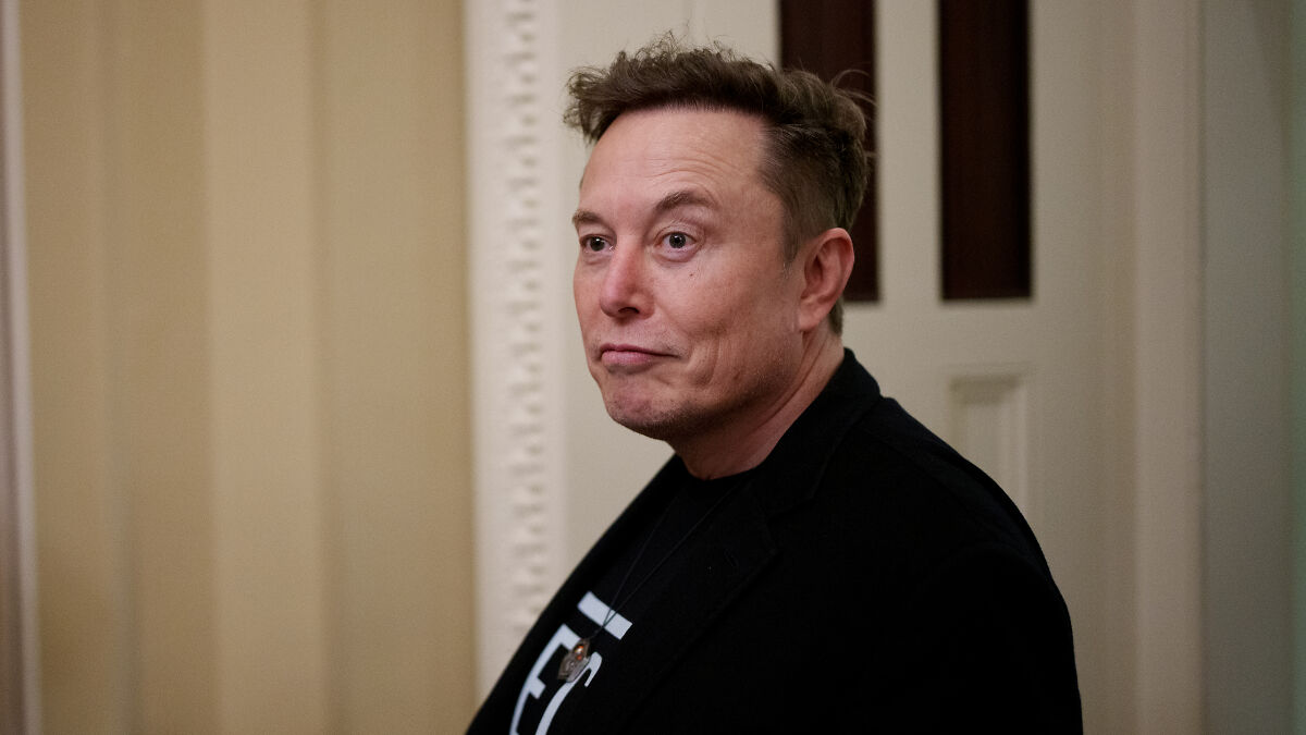 Elon Musk in a casual black jacket indoors, linked to Netflix boycott over pro-trans cartoon controversy.