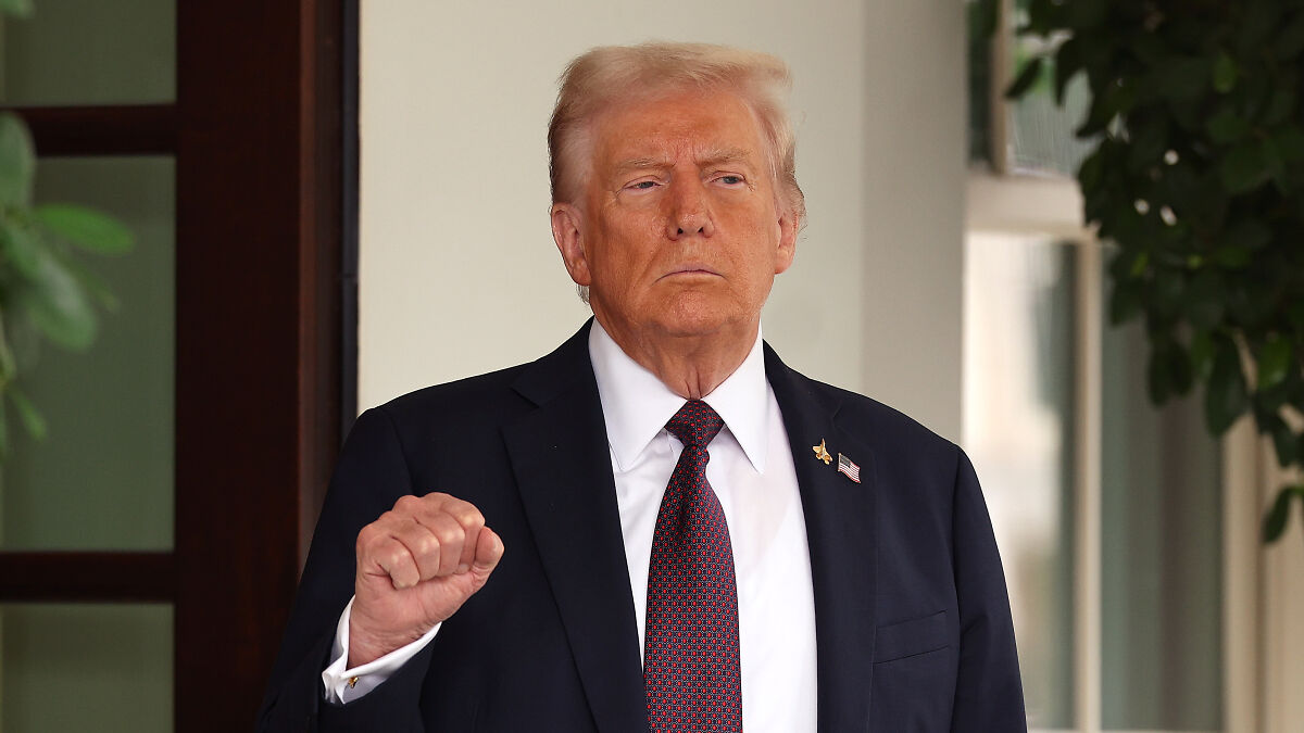 Donald Trump raising fist outdoors, in a suit and tie, related to Project 2025 and discussions on cutting Democratic agencies.