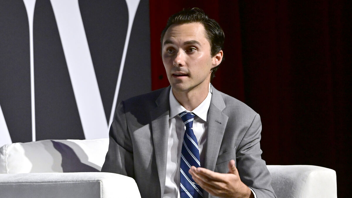Man in gray suit and blue striped tie speaking during an event about David Hogg PAC spending and Young Dems primaries.
