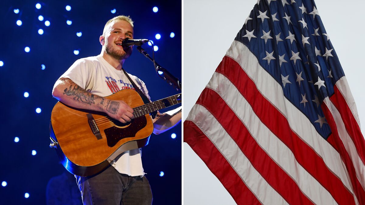 Country musician performing with guitar on stage alongside a waving American flag representing MAGA controversy.