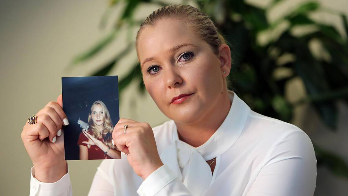 Virginia Giuffre holding a photograph, looking serious, related to allegations involving a well-known prime minister.