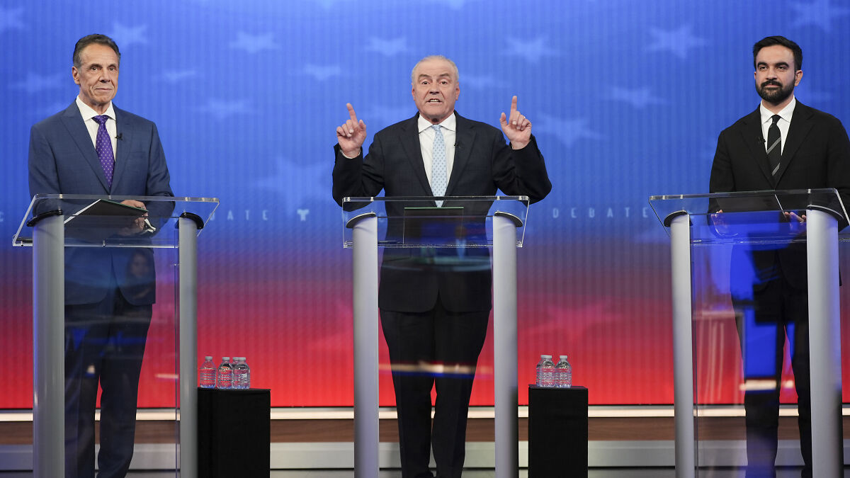 Three men at podiums during a NYC mayoral debate, featuring Zohran Mamdani and political candidates in suits.