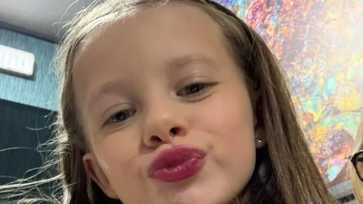 Young girl with long hair wearing lipstick, posing for a close-up selfie showing amazing little girl spirit.