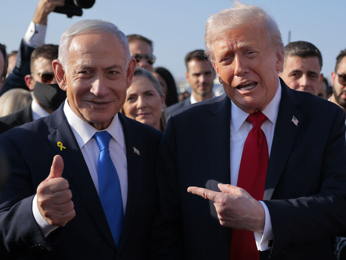 Donald Trump in a suit pointing while standing next to another man, highlighting the Trump melts down over Time Magazine photo hair issue.