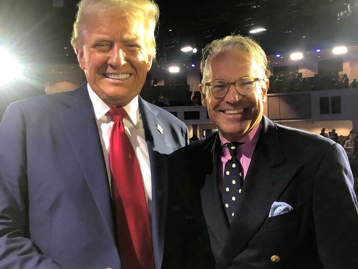 Donald Trump and another man smiling together at an indoor event with bright stage lighting, Mar-a-Lago setting. Donald Trump and another man smiling together at an indoor event with bright stage lighting, Mar-a-Lago setting.