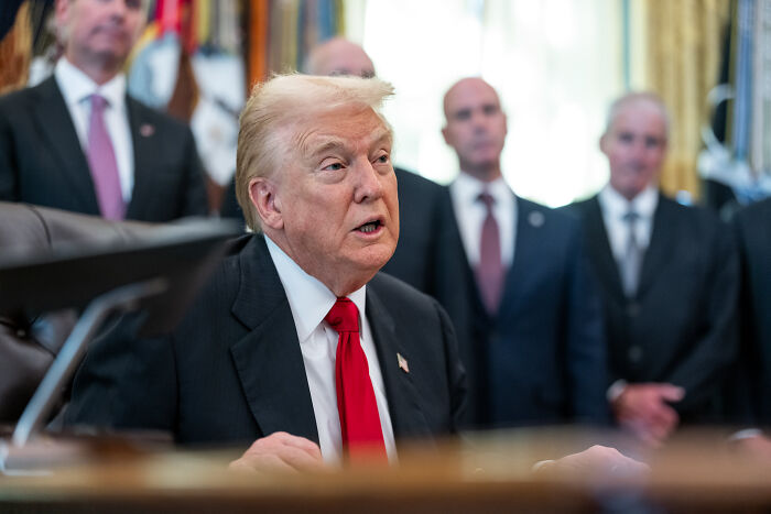 Donald Trump speaking at a desk during a meeting with aides in the background, related to MAGA voter grocery prices. Donald Trump speaking at a desk during a meeting with aides in the background, related to MAGA voter grocery prices.