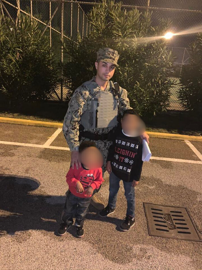 Navy sailor in uniform standing outdoors at night with two young children in casual clothes near a parking lot. Navy sailor in uniform standing outdoors at night with two young children in casual clothes near a parking lot.