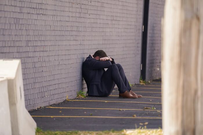Man in tears sitting on ground by a wall, emotional after running to follow disappeared wife at ICE facility. Man in tears sitting on ground by a wall, emotional after running to follow disappeared wife at ICE facility.