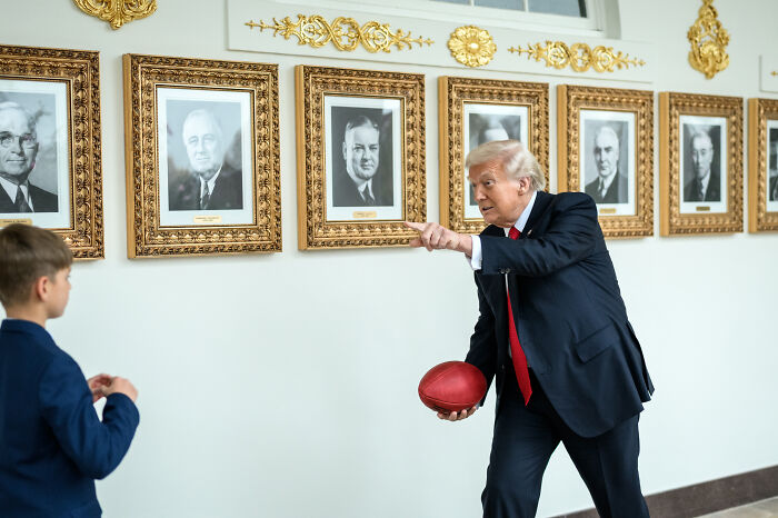 Donald Trump in a suit holding a football and interacting with his grandson, highlighting walking and health concerns discussed online.