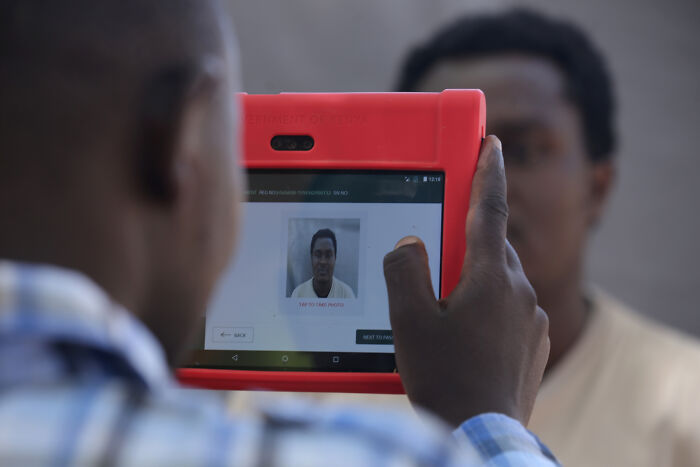 Person using a handheld device to capture biometric data as part of migration control surveillance systems. Person using a handheld device to capture biometric data as part of migration control surveillance systems.