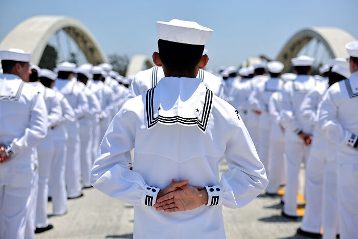 Navy sailor standing in formation wearing white uniform with sailor hat during a ceremonial event outdoors. Navy sailor standing in formation wearing white uniform with sailor hat during a ceremonial event outdoors.