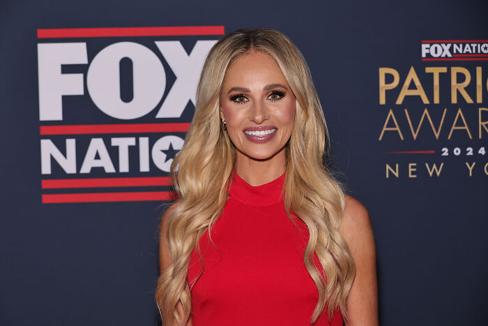Tomi Lahren smiling in a red dress at a Fox Nation event, related to social media roasts and political discussions. Tomi Lahren smiling in a red dress at a Fox Nation event, related to social media roasts and political discussions.