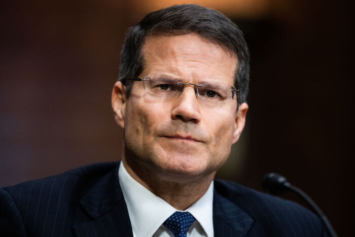 Man in suit and glasses with serious expression, symbolizing concern over Trump tax repayments and legal issues.
