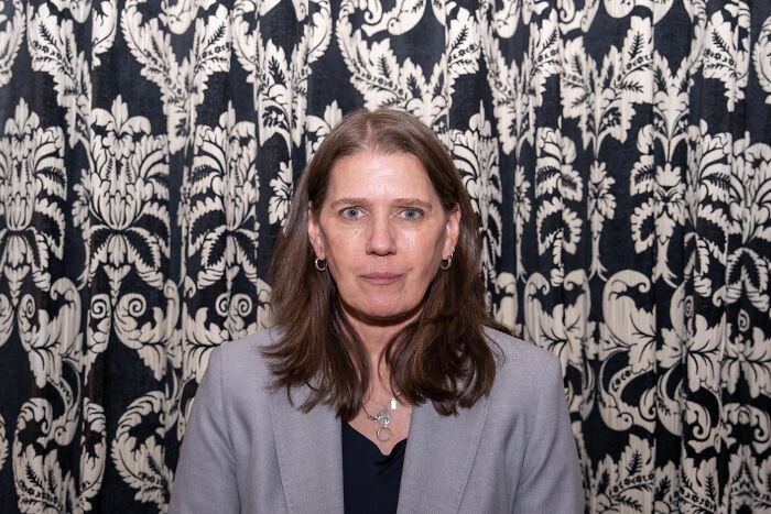 Woman with brown hair wearing a gray blazer against patterned background discussing Trump’s niece dementia claims. Woman with brown hair wearing a gray blazer against patterned background discussing Trump’s niece dementia claims.