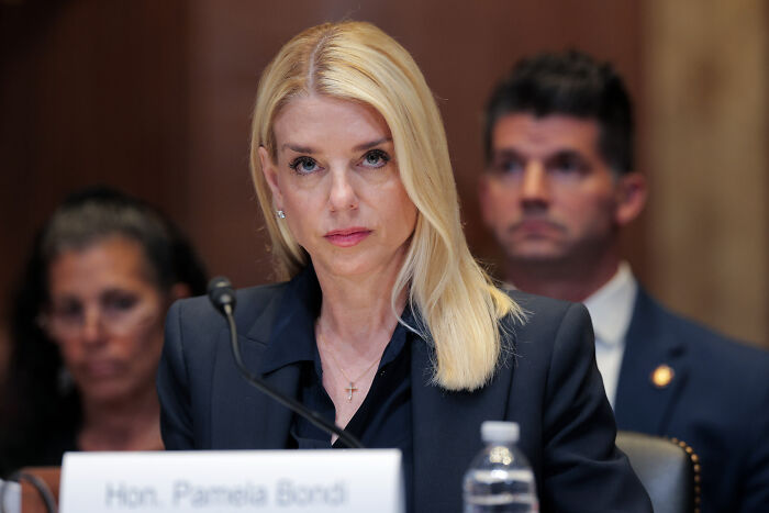 Blonde woman in formal attire seated at hearing, representing DOJ resignation letters related to Trump administration.