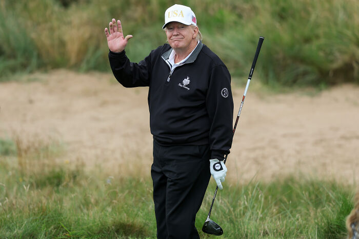 Donald Trump on a golf course waving, highlighting Trump golf trips cost taxpayers millions in government expenditures. Donald Trump on a golf course waving, highlighting Trump golf trips cost taxpayers millions in government expenditures.