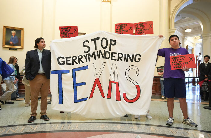 Protesters holding a stop gerrymandering Texas banner in a government building ahead of the 2026 midterms battle for house seats.