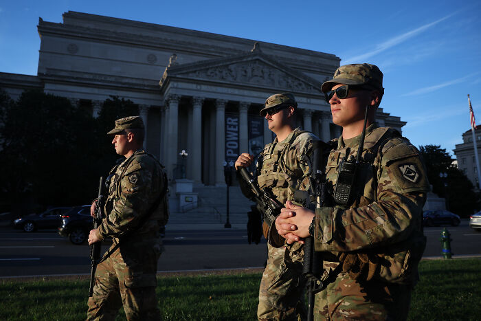 National Guard soldiers in uniform patrolling in front of a government building in Washington during daylight hours. National Guard soldiers in uniform patrolling in front of a government building in Washington during daylight hours.