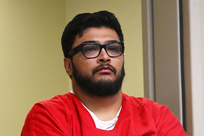 Jake Haro wearing glasses and a red prison uniform during a courtroom proceeding for torturing and k*****g baby Emmanuel.