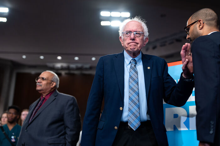 Older man in a blue suit and striped tie at a public event, symbolizing democratic socialism in NYC politics. Older man in a blue suit and striped tie at a public event, symbolizing democratic socialism in NYC politics.