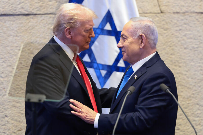 Donald Trump and Israeli leader warmly greeting each other in front of Israel flag during a formal event in 2025. Donald Trump and Israeli leader warmly greeting each other in front of Israel flag during a formal event in 2025.