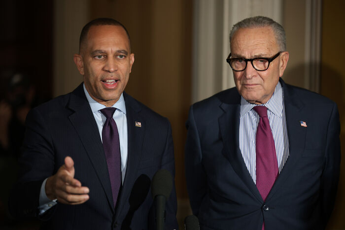 Two men in suits at a podium speaking during a political event, related to White House trolling Dems. Two men in suits at a podium speaking during a political event, related to White House trolling Dems.