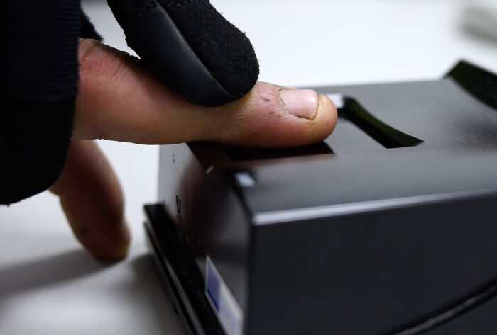 Close-up of a finger scanning on a biometric device representing migration control in surveillance states and data clouds. Close-up of a finger scanning on a biometric device representing migration control in surveillance states and data clouds.