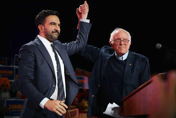 Zohran Mamdani and Bernie Sanders raising hands together at a democratic socialism event in NYC. Zohran Mamdani and Bernie Sanders raising hands together at a democratic socialism event in NYC.