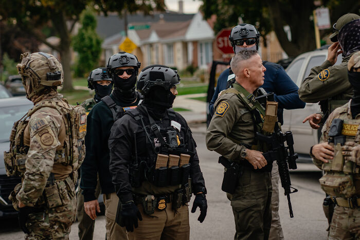 Heavily armed ICE agents and tactical police officers gathered on a Chicago street during an enforcement operation.