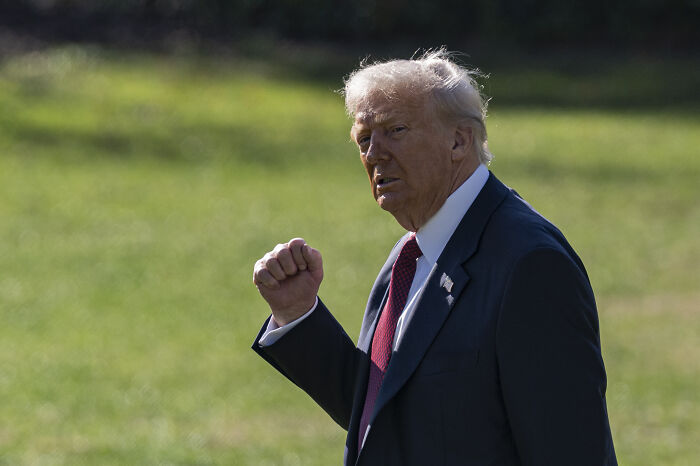 Former president in a dark suit raising fist outdoors, symbolizing the battle for House seats ahead of 2026 midterms.