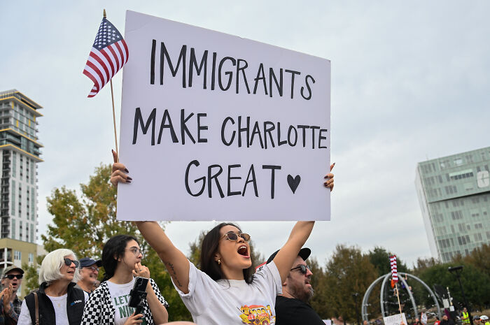 Protesters in Charlotte holding signs supporting immigrants during a rally against ICE raids and immigration policies. Protesters in Charlotte holding signs supporting immigrants during a rally against ICE raids and immigration policies.