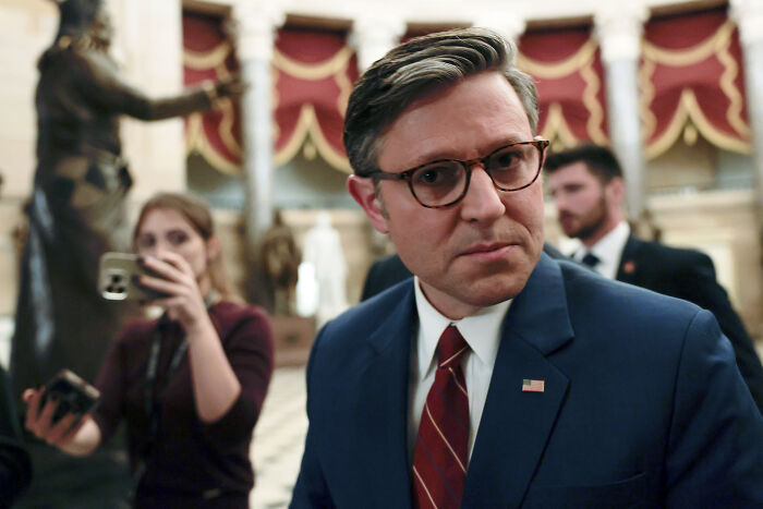 Man in a suit and glasses inside a government building amid Trump contact and Epstein files release discussions.