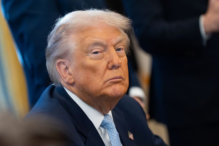 Donald Trump in a suit and blue tie, looking serious during a formal event discussing dementia concerns from family claims. Donald Trump in a suit and blue tie, looking serious during a formal event discussing dementia concerns from family claims.