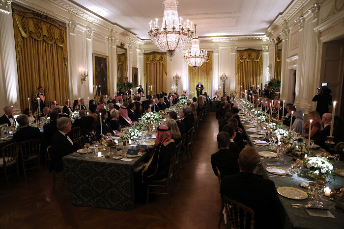 Formal White House dinner with Melania Trump and Saudi Crown Prince in elegant room with chandeliers and long banquet tables.
