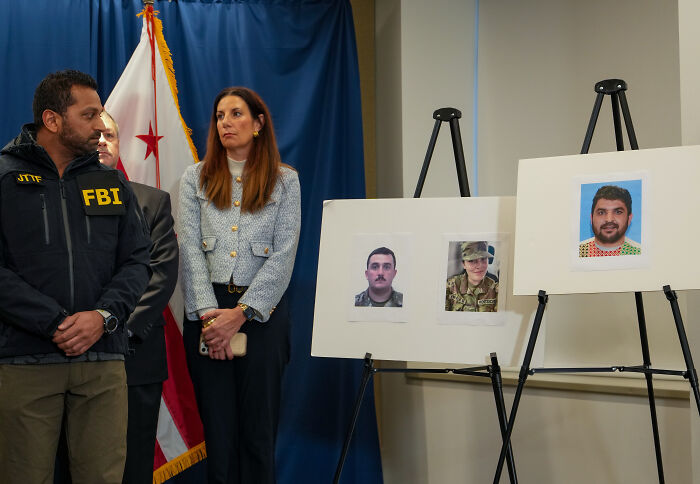 FBI agent and officials at press conference with photos of National Guard member and shooting suspects displayed on easels. FBI agent and officials at press conference with photos of National Guard member and shooting suspects displayed on easels.