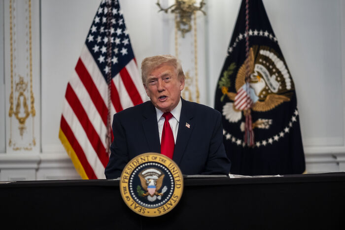 Former President speaking at a podium with flags behind, related to National Guard member and D.C. shooting case. Former President speaking at a podium with flags behind, related to National Guard member and D.C. shooting case.
