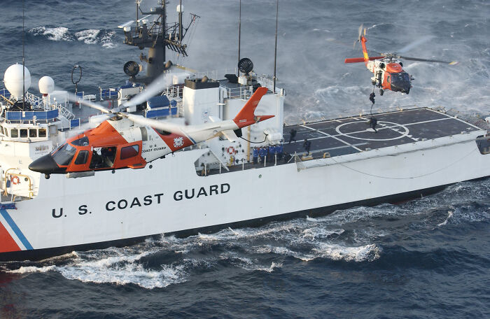 U.S. Coast Guard ship with helicopters in flight showcasing redesigned aesthetic features on the vessel. U.S. Coast Guard ship with helicopters in flight showcasing redesigned aesthetic features on the vessel.