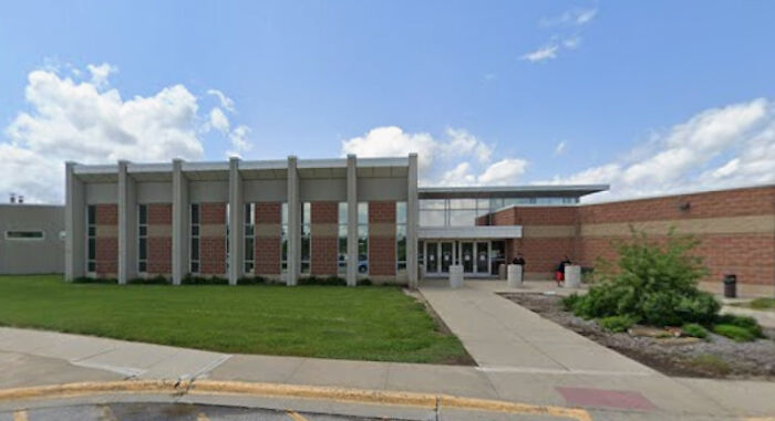 Modern brick and concrete building exterior with a lawn under partly cloudy blue sky related to ICE nearly deports woman.