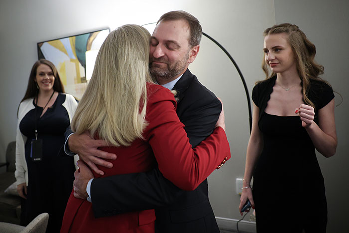 Man in suit hugging woman in red jacket as Virginia turns blue in a sweeping victory, marking a heavy blow for Trump. Man in suit hugging woman in red jacket as Virginia turns blue in a sweeping victory, marking a heavy blow for Trump.